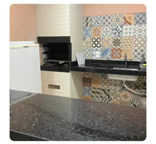 a kitchen with a sink and a tile wall at Casa piscina 3 quartos in Goiânia