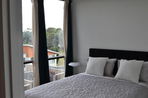 sypialnia z łóżkiem i dużym oknem w obiekcie ZMITH Apartment - BROOKE Canberra w mieście Belconnen