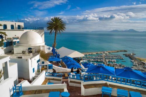 widok na ośrodek z niebieskimi krzesłami i ocean w obiekcie باردو الحناية w mieście Tunis