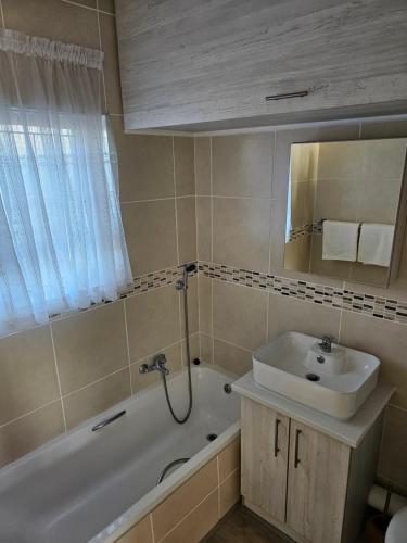 ein Badezimmer mit einem Waschbecken, einer Badewanne und einem Waschbecken in der Unterkunft Magna seaview in Jeffreys Bay