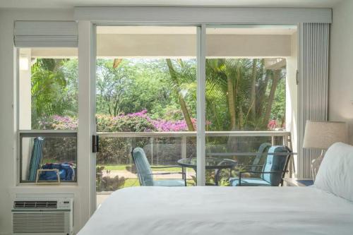 a bedroom with a bed and a view of a patio at Walkable to Beach, Restaurants & Shops. Remodeled! in Wailea