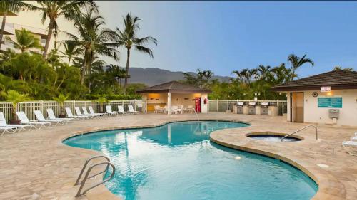 a swimming pool with chairs and a building at Walkable to Beach, Restaurants & Shops. Remodeled! in Wailea