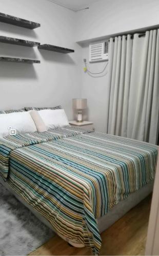 ein Schlafzimmer mit einem Bett mit einer bunten Decke darauf in der Unterkunft Modern 2BR Condo with Fiber Net and Netflix in Davao City