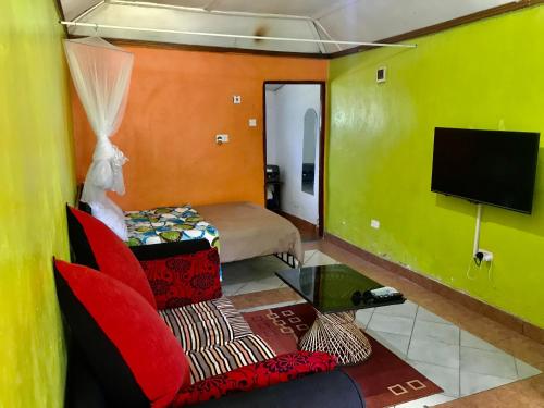 Cette petite chambre comprend un lit et une télévision. dans l'établissement Stone Cottages, Kilimani, à Nairobi