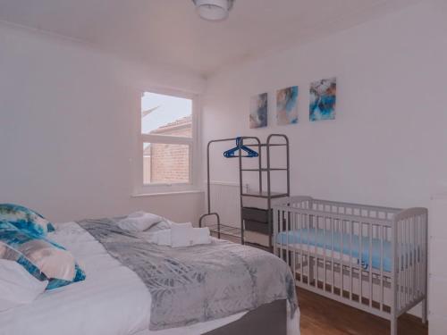 a white bedroom with a crib and a window at Budget 2BDR apartment 6PPL pets in Teddington