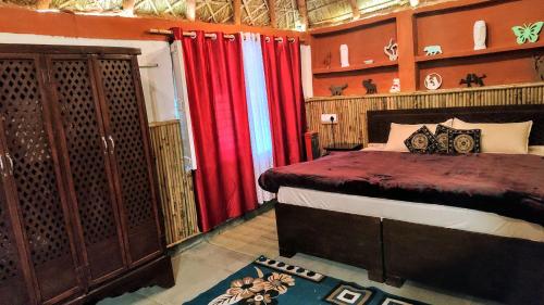 a bedroom with a bed and red curtains at Shivoham the earthen Home in Dehradun