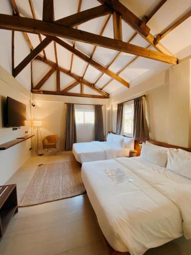 a bedroom with two beds and a tv at Nacpan Beach Villas Managed by H Hospitality Group in El Nido
