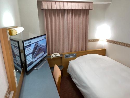 a hotel room with a bed and a flat screen tv at Hotel Alpha-One Izumo in Izumo