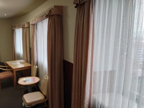 a room with a window with curtains and a table at Ueno Frex Hotel in Iga