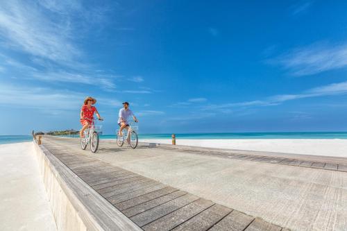 two people riding bikes on a boardwalk on the beach at Jawakara Islands Maldives in Lhaviyani Atoll