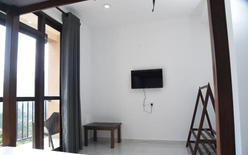 a living room with a tv on a white wall at Ever Breeze Ella Hotel in Ella