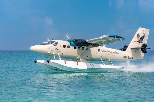 a small plane is flying over the water at Jawakara Islands Maldives in Lhaviyani Atoll