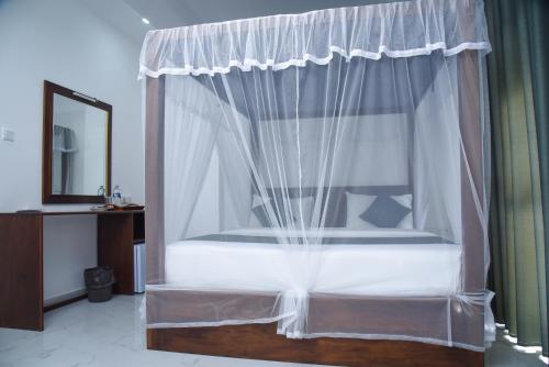 a bedroom with a canopy bed with white curtains at Ever Breeze Ella Hotel in Ella