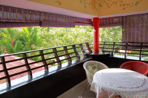 a balcony with a table and chairs and a window at Bella Boutique Homestay in Alleppey