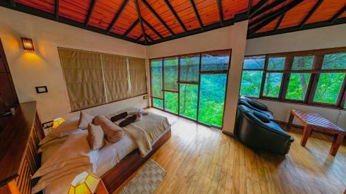 a bedroom with a large bed and large windows at Tea Cottage - Luxury Tea Resort & Spa - Nawalapitiya in Nawalapitiya