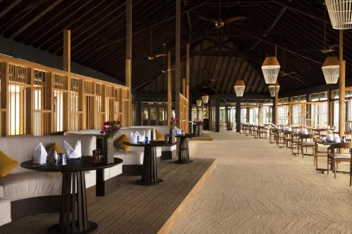 a restaurant with tables and chairs in a building at Jawakara Islands Maldives in Lhaviyani Atoll