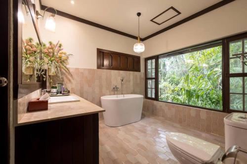 a bathroom with a tub and a sink and a toilet at Lanna Charm 5BR Villa in Maerim in Mae Rim
