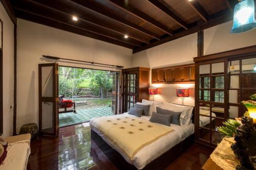 a bedroom with a large bed and a sliding glass door at Lanna Charm 5BR Villa in Maerim in Mae Rim