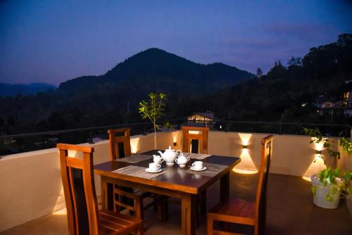 a table on a balcony with a view of a mountain at Ever Breeze Ella Hotel in Ella