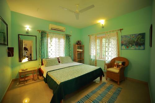 a bedroom with a bed and a mirror and a chair at Bella Homestay Kerala in Alleppey