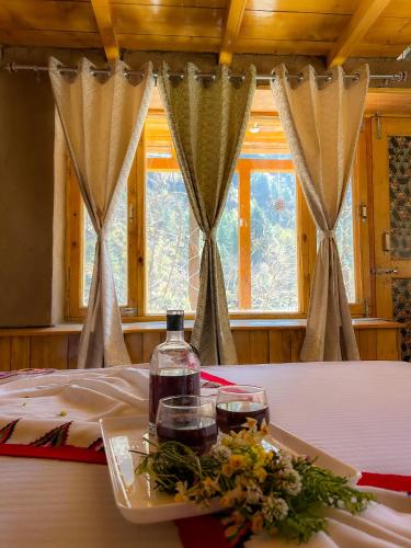 a table with two glasses and a bottle of wine at Sainj Riverside Cottages in Sainj