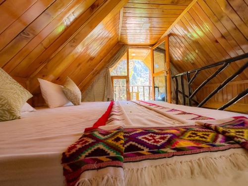 a bed in a room with a wooden ceiling at Sainj Riverside Cottages in Sainj