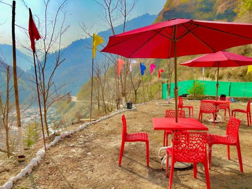 a group of red tables and chairs with red umbrellas at Sainj Riverside Cottages in Sainj