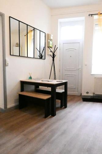 Cette chambre comprend une table, un banc et un miroir. dans l'établissement Charmant petit pont Ardennais/cosy/T1/wifi/parking, à Sedan