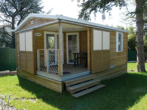a wooden cabin with a porch in the grass at CAMPING ONLYCAMP DU MOULIN in Clisson
