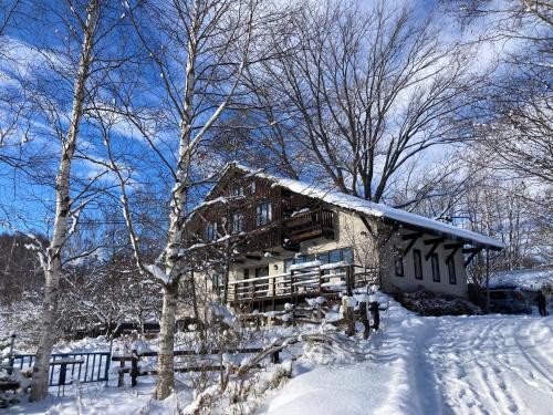 中富良野町にあるペンション ラクレットの雪の中の木々の丸太小屋