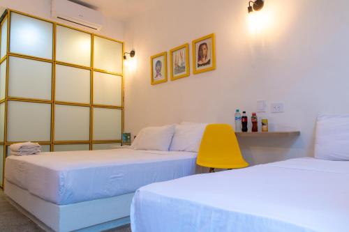 a room with two beds and a yellow chair at OASIS TROPICAL HOTEL in Santa Marta