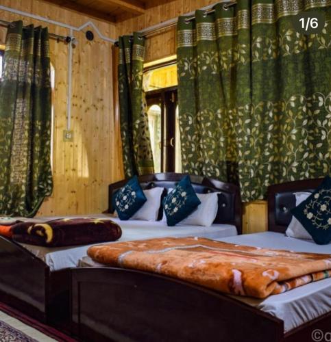 2 Betten in einem Zimmer mit grünen Vorhängen in der Unterkunft Hotel kaka palace Gurez in Kanzalwan