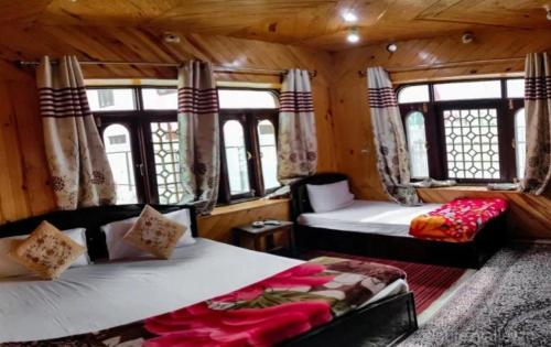 Zimmer mit 2 Betten, einem Sofa und Fenstern in der Unterkunft Hotel kaka palace Gurez in Kanzalwan