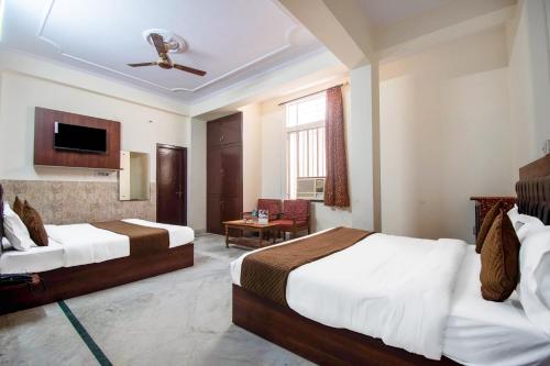 ジャイプールにあるHotel Marwalのベッド2台とテレビが備わるホテルルームです。