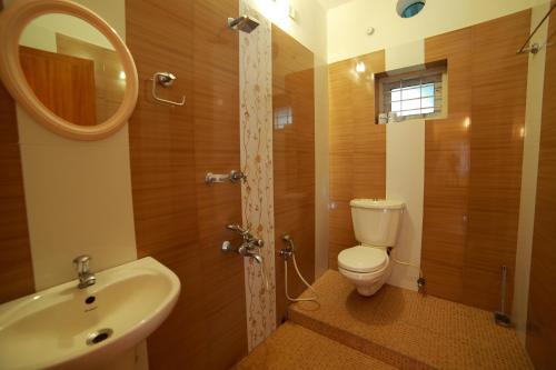 bagno con servizi igienici, lavandino e specchio di Bella Homestay Kerala a Alleppey