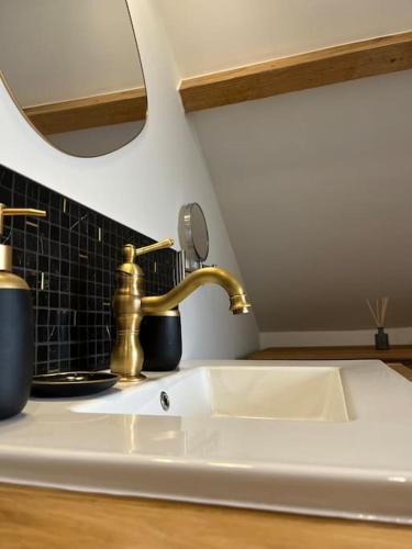 a kitchen sink with a gold faucet and a mirror at Joly Cottage in Corbion