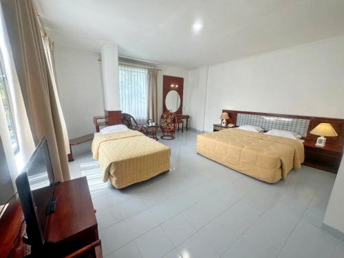a hotel room with two beds and a mirror at Hotel Wisata Indah Sibolga in Sibolga