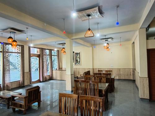 a restaurant with wooden chairs and tables and windows at Great Himalayan Nature View Resort in Banjār