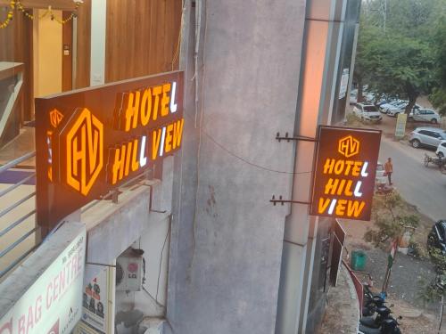 un bâtiment avec des panneaux de néon sur son côté dans l'établissement Hotel Hill View, à Gandhinagar