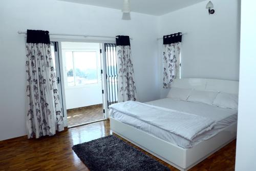 - un lit blanc dans une chambre avec fenêtre dans l'établissement HAILSTONE HOME STAY, à Ooty
