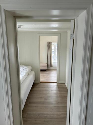 a room with a bed and a hallway with a mirror at Finsnes Gaard in Finnsnes
