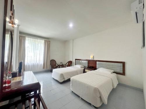 Habitación de hotel con 2 camas y escritorio en Hotel Wisata Indah Sibolga en Sibolga