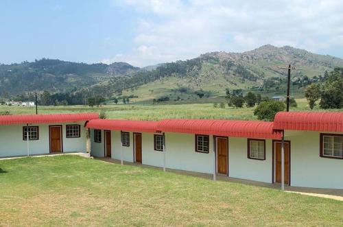 a row of buildings with red roofs in a field at African Violet in Mbabane