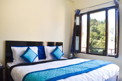 ein Bett mit blauen und weißen Kissen und einem Fenster in der Unterkunft Atithi Home Stay - Himalayas view in Chaukori