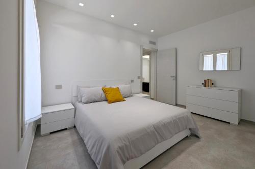 a white bedroom with a bed with a yellow pillow at Minimal Apt Centro Wifi Clima by WeHostYou in Porto San Giorgio