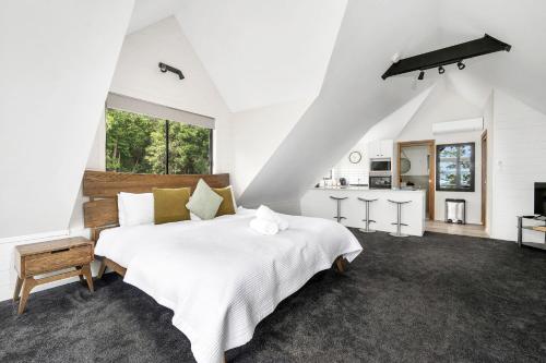 a white bedroom with a large bed and a kitchen at Valley View Studio, Kangaroo Valley in Beaumont