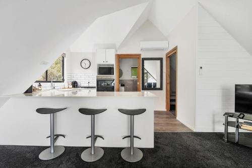 a kitchen with a white counter and stools at Valley View Studio, Kangaroo Valley in Beaumont