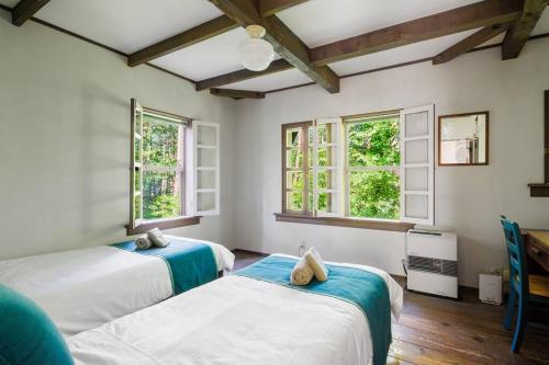 two beds in a room with two windows at レイドバックシャレー in Hakuba