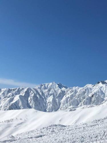 a snow covered mountain range in the distance at レイドバックシャレー in Hakuba