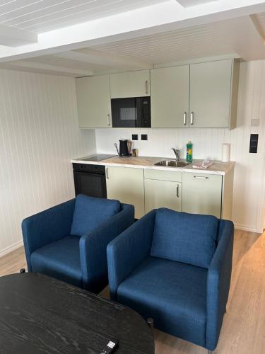 a kitchen with two blue chairs and a table at Finsnes Gaard in Finnsnes